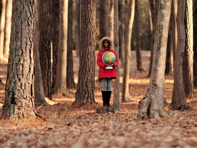 girl holding globe in woods demonstrating net zero