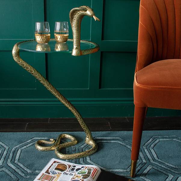 Brass snake supporting a piece of glass to make a coffee table
